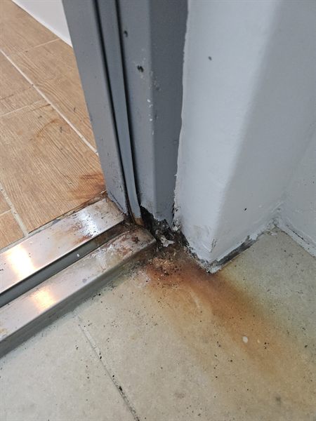 안성 아파트 다용도실 방화문 시공 전 - 물기가 고이는 문틀 하부가 부식되어 철판이 삭아 벌어진 상태