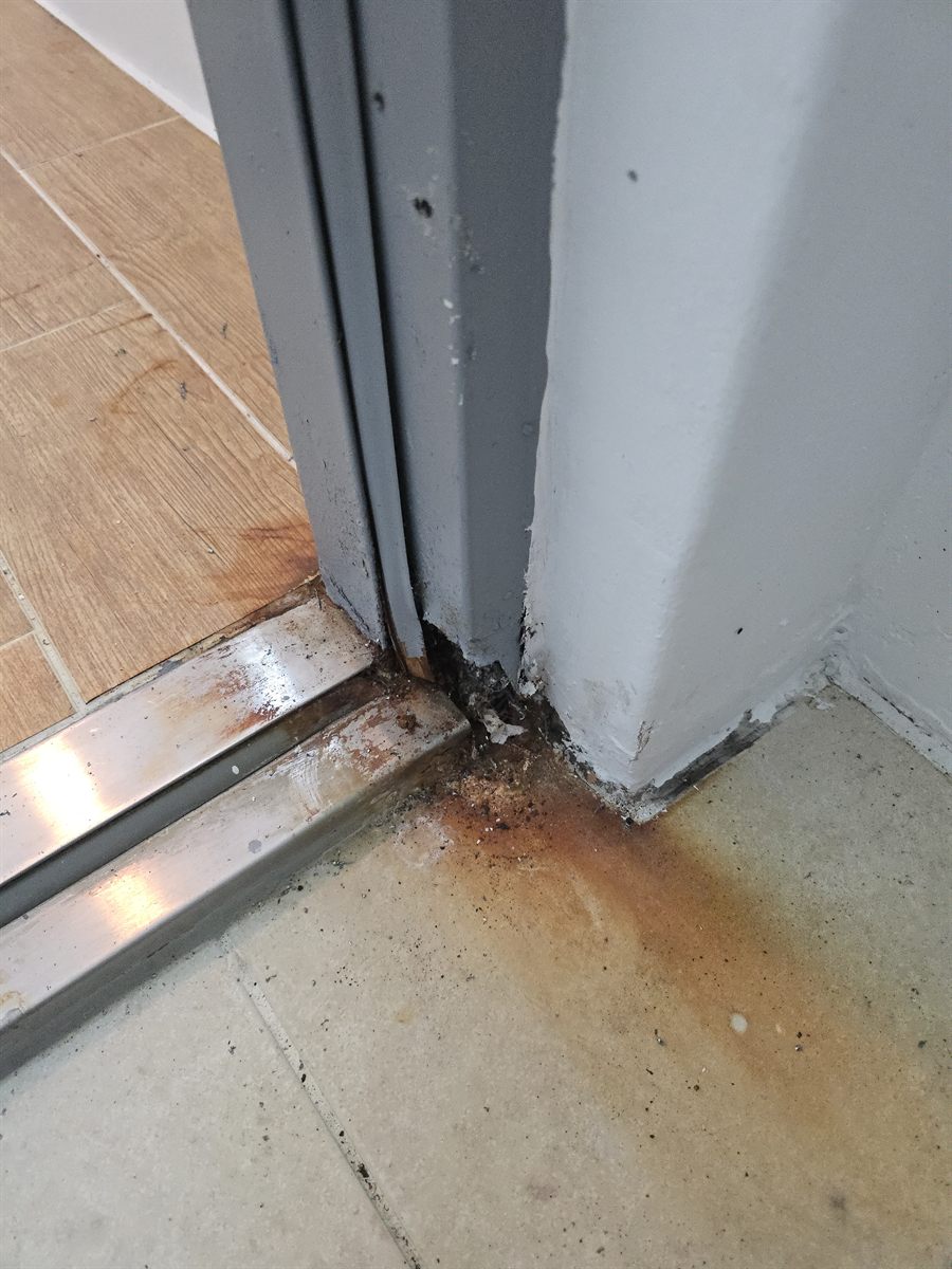 안성 아파트 다용도실 방화문 시공 전 - 물기가 고이는 문틀 하부가 부식되어 철판이 삭아 벌어진 상태