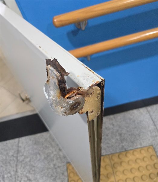 화성 병원 화장실 방화문 시공 전 - 상시 습기로 문틀 하부가 부식되어 철판이 삭고 표면이 벗겨진 상태